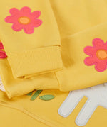 Frugi kids jumper laid flat showing a close up of the cute flower applique on the lower arms on yellow organic cotton fabric