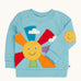 Frugi organic cotton jumper laid flat. In light blue with a smiling sun design on the front and a smiling face patch on the sleeve.