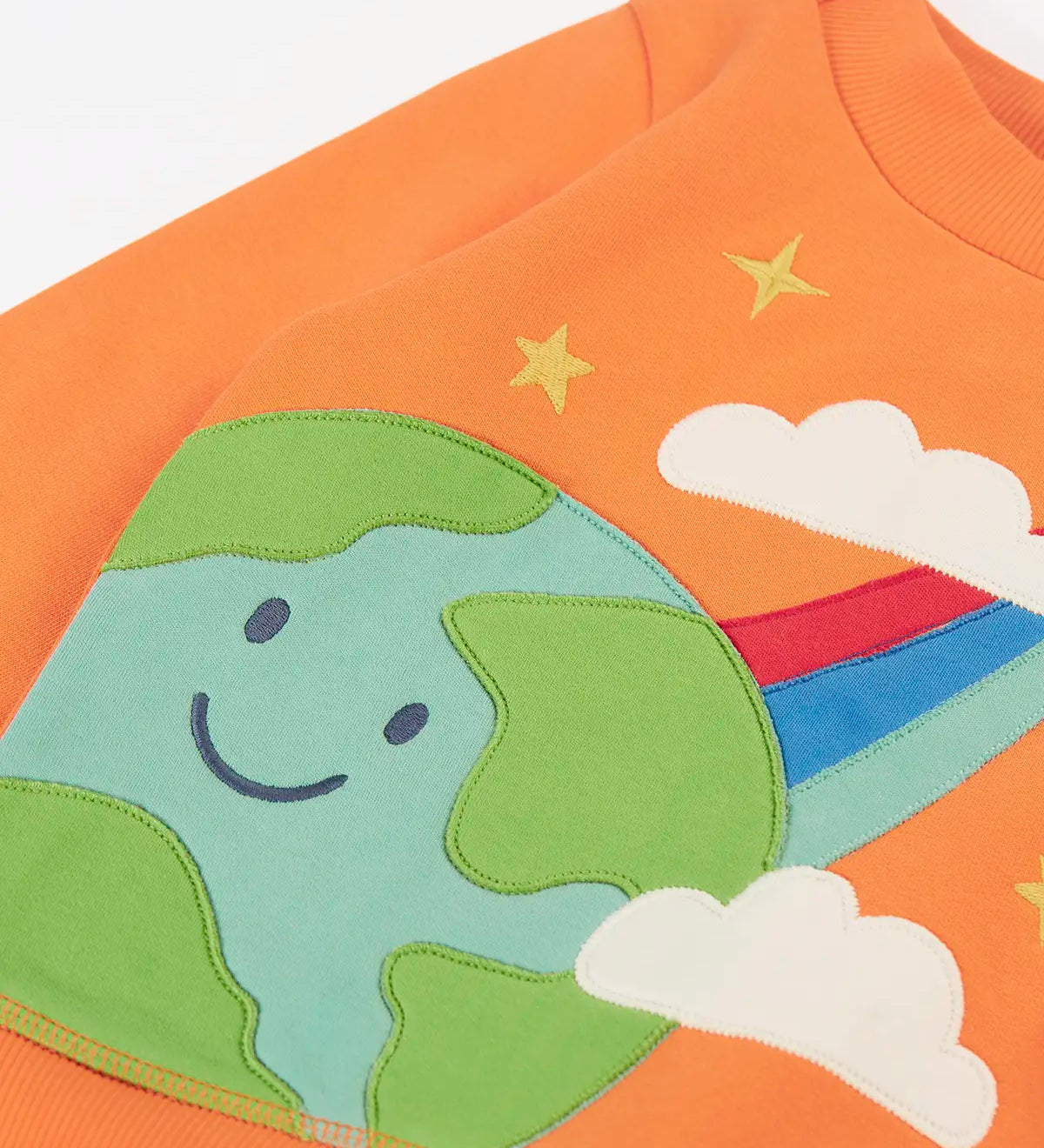 Frugi kids jumper laid flat showing a close up of the cute planet earth and star applique on the front on orange organic cotton fabric