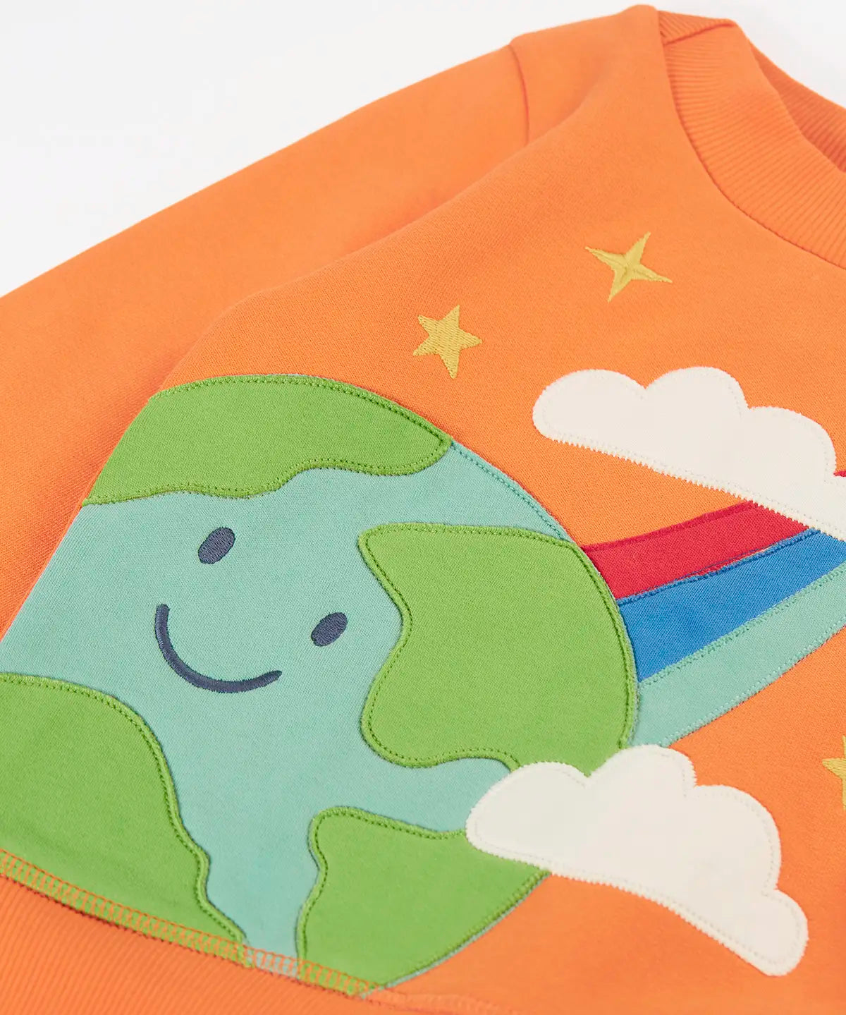 Frugi kids jumper laid flat showing a close up of the cute planet earth and star applique on the front on orange organic cotton fabric