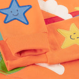 Frugi kids jumper laid flat showing a close up of the cute star applique on the lower arms on orange organic cotton fabric