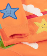 Frugi kids jumper laid flat showing a close up of the cute star applique on the lower arms on orange organic cotton fabric