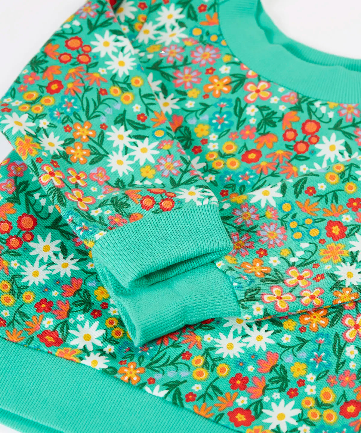 Frugi kids jumper laid flat showing close up of the repeating floral print and elasticated turn up cuffs on green organic cotton fabric