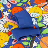 A closer look at the royal blue, elasticated ribbed wrist cuffs on the Frugi Snuggle Suit - Retro Happy. The image also shows the Retro Happy print and the zip on the snuggle suit