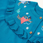 A closer look at the beautiful embroidered fairies on the Frugi Romi Ruffle Cardigan - Deep Water/Fairies. The image also shows the ruffled collar fabric, and stars surrounding the fairies.