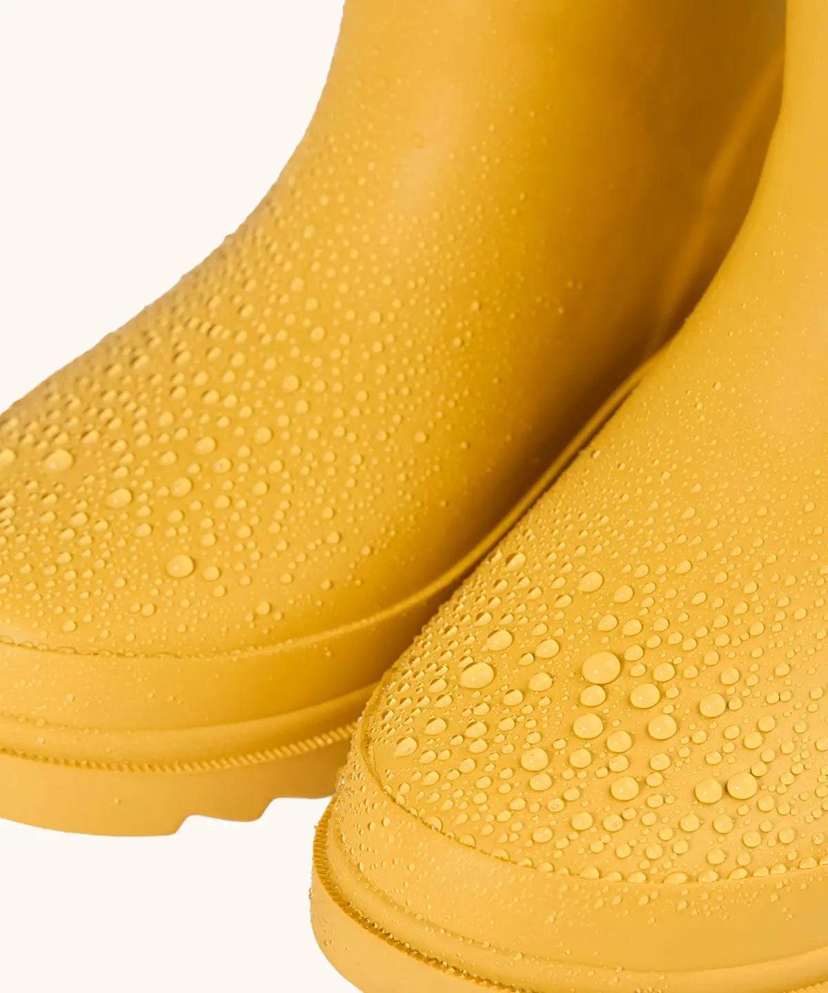 Frugi natural rubber, waterproof puddle buster wellingtons in yellow showing close up of the water beading