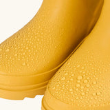 Frugi natural rubber, waterproof puddle buster wellingtons in yellow showing close up of the water beading