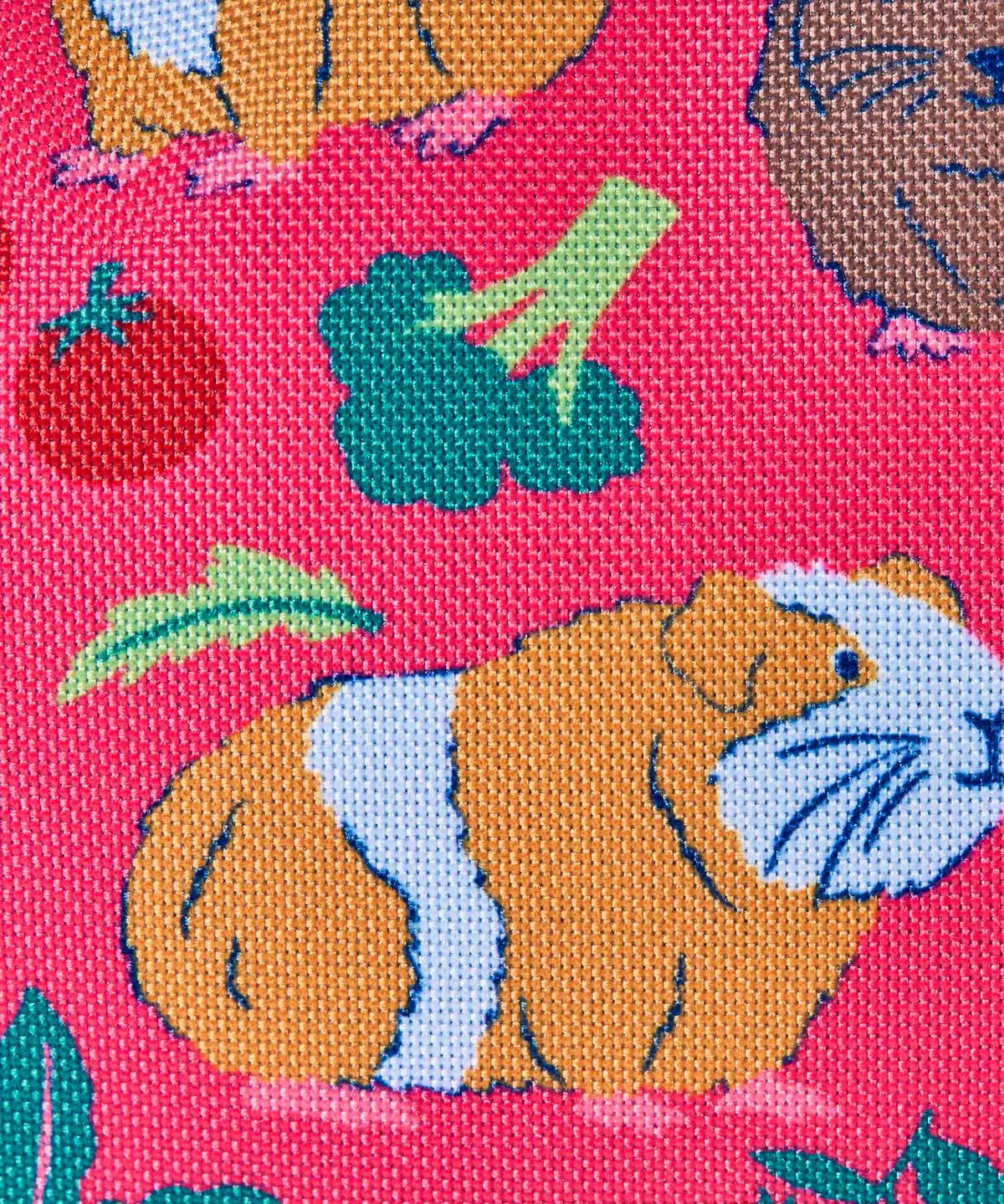 Frugi explorers backpack in guinea pig muddle showing repeating guinea pig and vegetables design on pink material