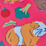 Frugi explorers backpack in guinea pig muddle showing repeating guinea pig and vegetables design on pink material