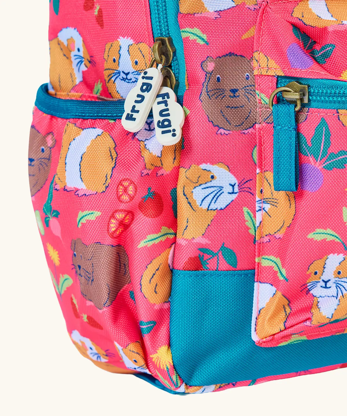 Frugi explorers backpack in guinea pig muddle showing the side pocket for holding a water bottle. 