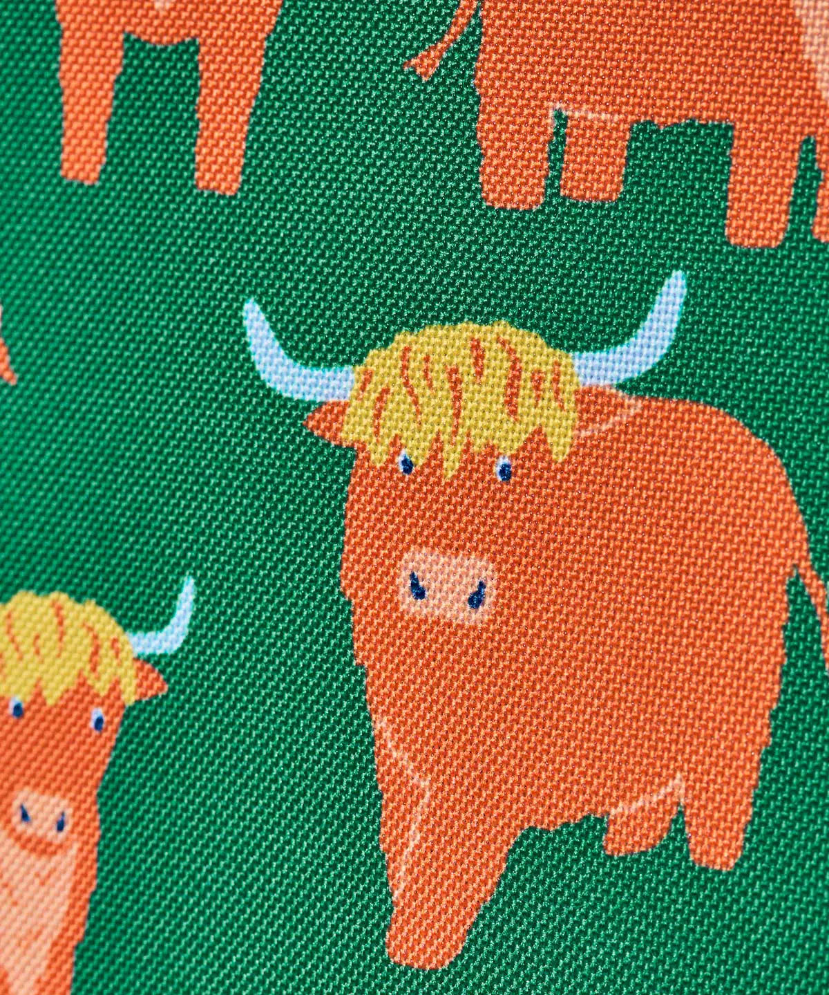 Frugi explorers backpack in green with showing close up of the repeating highland cow design.