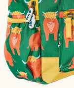 Side of Frugi explorers backpack in green with a repeating highland cow design showing the side pocket