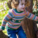 A child playing on trees and wearing the the Frugi fowey fairisle bear knitted jumper. A bright and colourful soft knitted jumper in a fairisle style