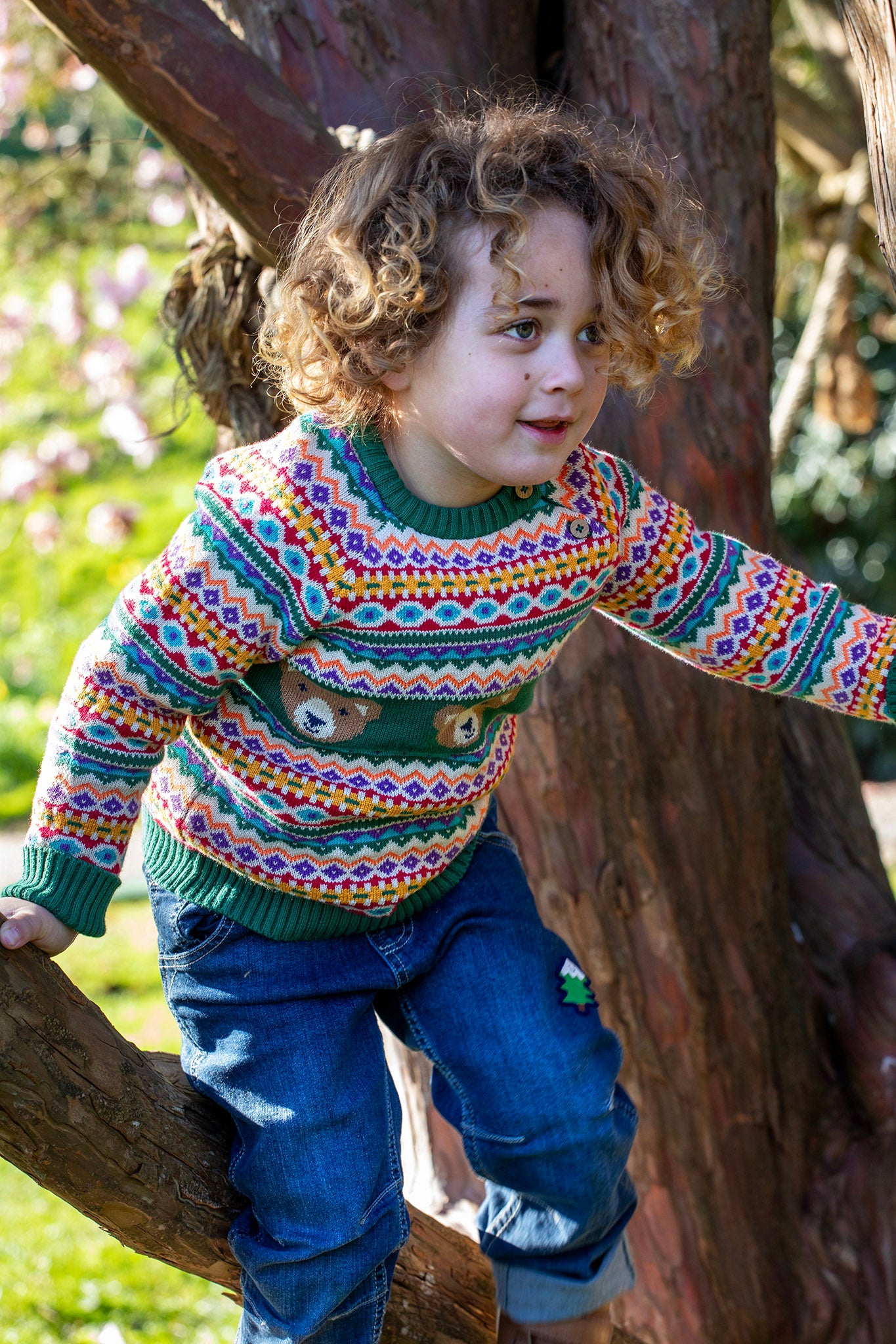 A child playing on trees and wearing the the Frugi fowey fairisle bear knitted jumper. A bright and colourful soft knitted jumper in a fairisle style