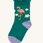 The green socks from the Frugi Freya Frilled Socks 3 Pack - Rainforest Friends. This sock has a lilac toe and heel, white flowers and a flamingo on emerald green fabric