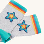 The grey pair of socks from the Frugi Rock My Socks - Stars 2 Pack. These grey socks have a rainbow star on them, and rainbow ankle cuffs