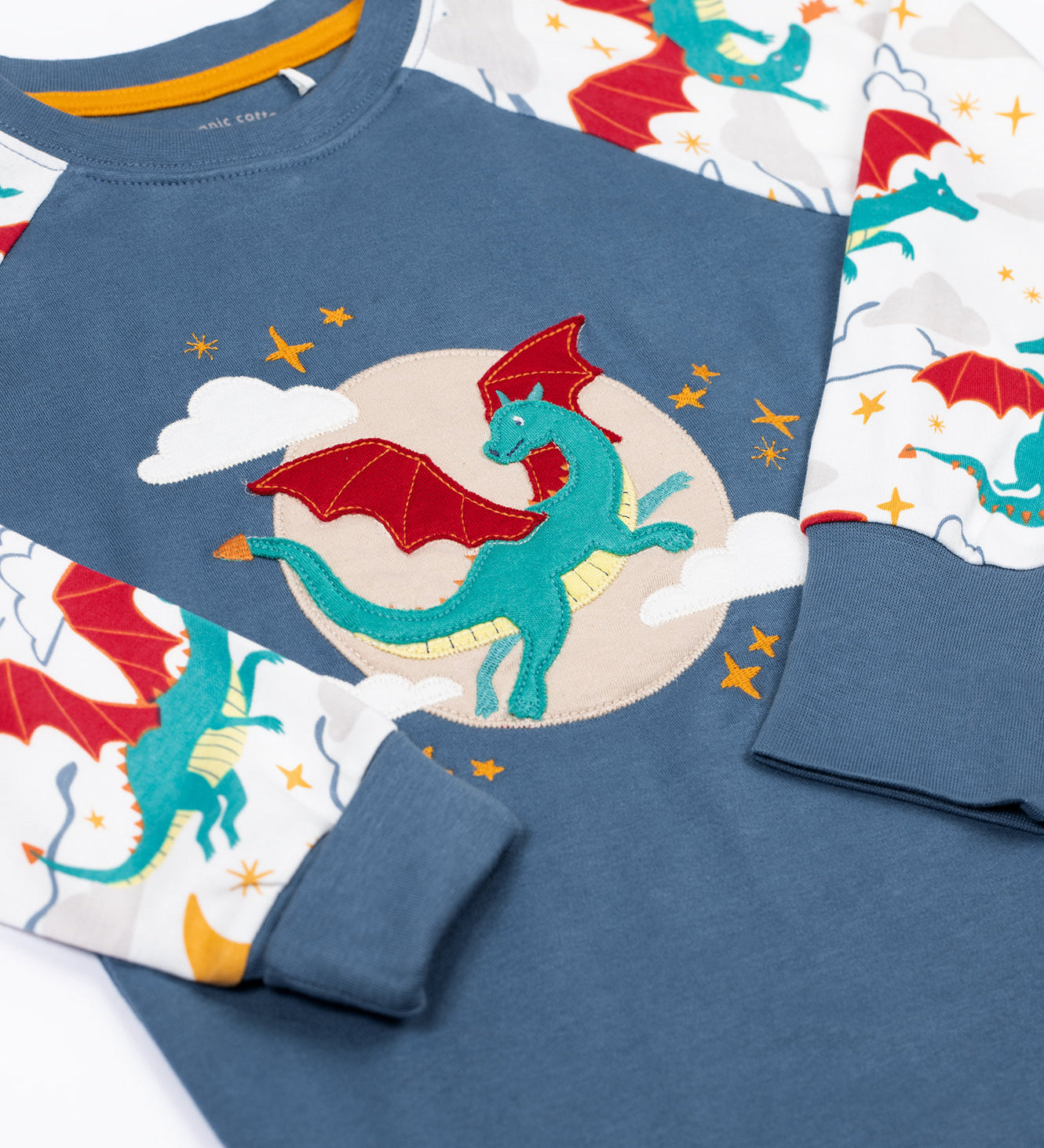 A close up of the green dragon applique on the Frugi dragon skies Jamie jim jam top available at Babipur. 