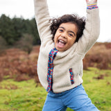 Girl wearing Frugi Juana Fleece jacket in cream with corduroy piping and pocket details in blue floral.