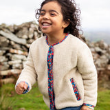Frugi Juana Fleece jacket in cream with Alpine Blooms corduroy piping, made from recycled polyester, worn by child.
