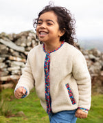 Frugi Juana Fleece jacket in cream with Alpine Blooms corduroy piping, made from recycled polyester, worn by child.