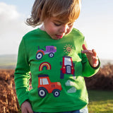 Front of child wearing Frugi's  GOTS organic cotton long sleeve top in green with playful tractor appliques 