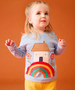 Small child wearing the Frugi's GOTS 100% organic cotton top in light blue showing the cute house on a rainbow applique on the front
