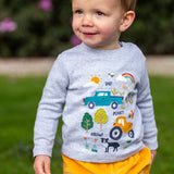 A toddler standing outside and wearing the Frugi kids adventure circular top in grey marl with farm inspired appliques on the front available at Babipur. 