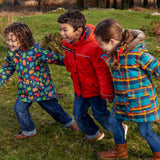 Kids playing on a grassy field and wearing Frugi's playtime, 3 in 1 rambler and a parka coat.