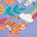 A closer look at the tiger applique with embroidered details, on the Frugi Ria Hoodie Dress - Grape/Stay Wild. Also shown is a small cloud with the start of the rainbow, applique leaves and the legs of the zebra