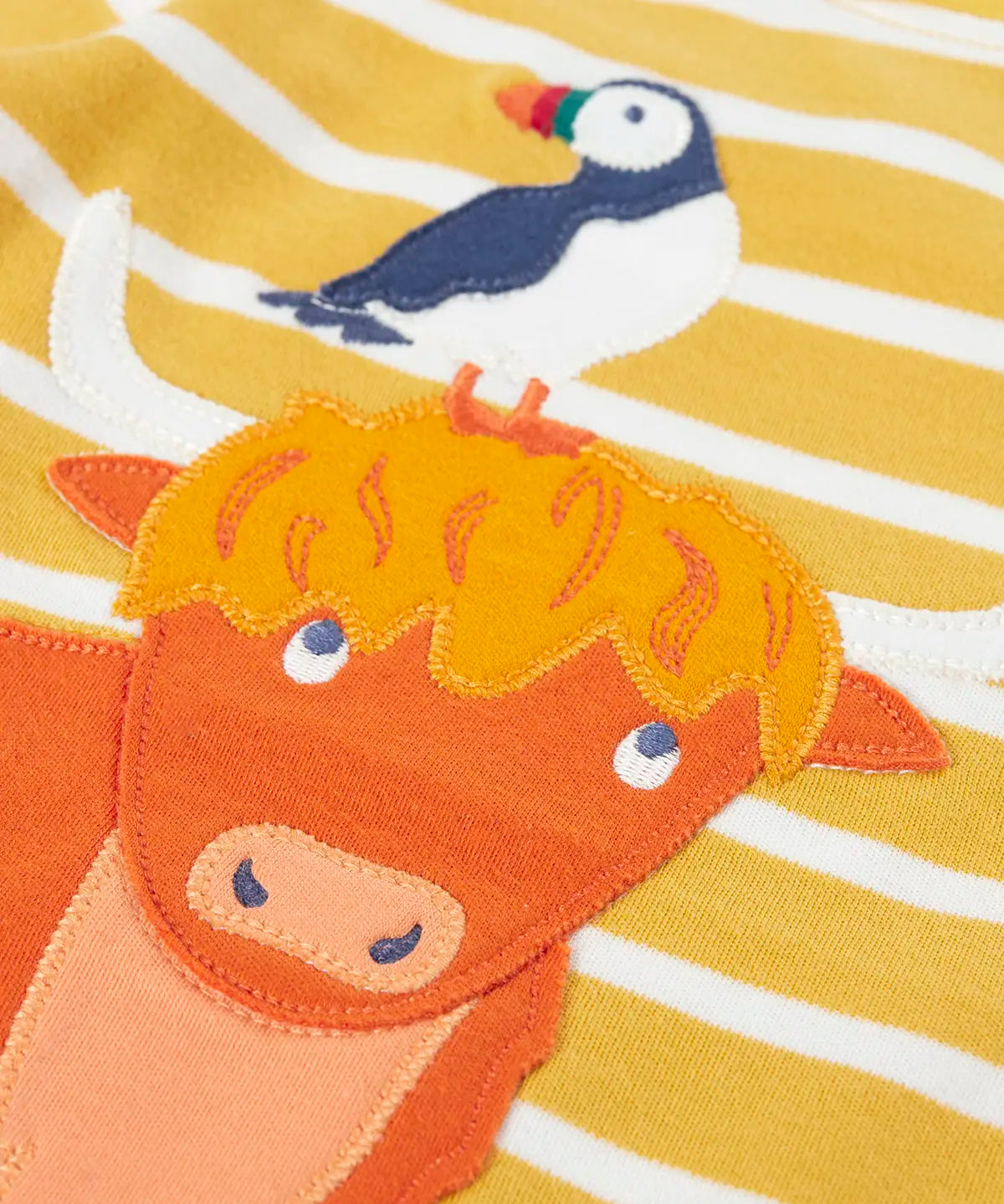 Frugi kids easy on top showing close up of a highland cow applique on yellow and white striped organic cotton fabric