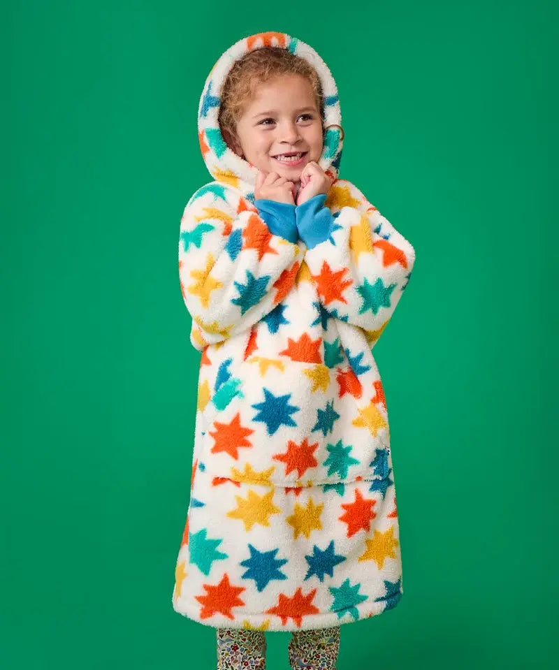 Frugi hooded fleece blanket in cosy cream with blue, orange and yellow star all-over print, worn by girl with hood up.