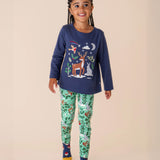 A child wearing the Frugi libby leggings in festive forest with the navy reindeer top as an outfit both available at Babipur. A GOTS organic cotton legging in mint green colour with a winter woodland inspired design.