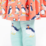 A closer look at the puffin print on the knees of the Frugi Norah Tights - Moss/Puffin, worn with a Frugi puffin dress