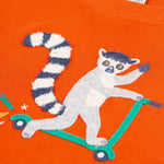 A look and the fun lemur, riding a scooter on the front of the Frugi Owen Top - Bonfire/Lemur