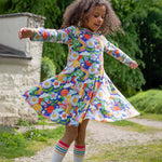 A child playing outside, twirling in the Frugi Sofia Skater Dress - Retro Happy, to show the movement and flow of the dress skirt.