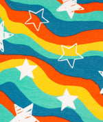 The wavy star print on the Frugi Cosy Amelia Dress - Wavy Stars, consists of wavy stripes in blue, green, yellow and red with white stars all over