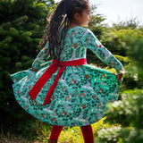 The back of a child wearing the Frugi party skater dress in festive forest available at Babipur showing the red tie around the waist and tied in a festive inspired bow.