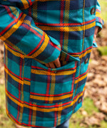 Small child wearing Frugi's Penhale tartan parka coat showing close up of side pocket with popper fastener