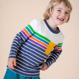 A child wearing the Frugi Piran pocket top in navy stripe available at Babipur. A long sleeve top in a striped design on GOTS organic cotton fabric. Features a yellow chest pocket