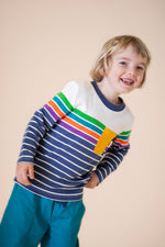 A child wearing the Frugi Piran pocket top in navy stripe available at Babipur. A long sleeve top in a striped design on GOTS organic cotton fabric. Features a yellow chest pocket