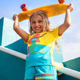 Child wearing Frugi's Poldhu hotchpotch short sleeve t-shirt in yellow and aqua with a mermaid patch and holding a skateboard