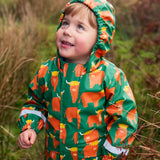 Small child wearing Frugi's waterproof puddle buster coat in highland grazing showing the fitted hood up