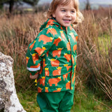 Small child wearing Frugi's waterproof puddle buster coat in highland grazing showing the side pocket and reflective strip on the cuff