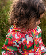 Child wearing the Frugi waterproof puddle buster coat in purrfect ponies showing the repeating cat and pony design inner