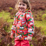 Small child wearing Frugi waterproof puddle buster coat in purrfect ponies showing the side pocket and reflective strip on the cuff