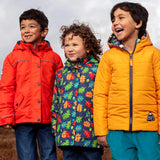 Frugi's orange rambler, navy with repeating acorn playtime and yellow reversible toasty coats worn by small children in a field