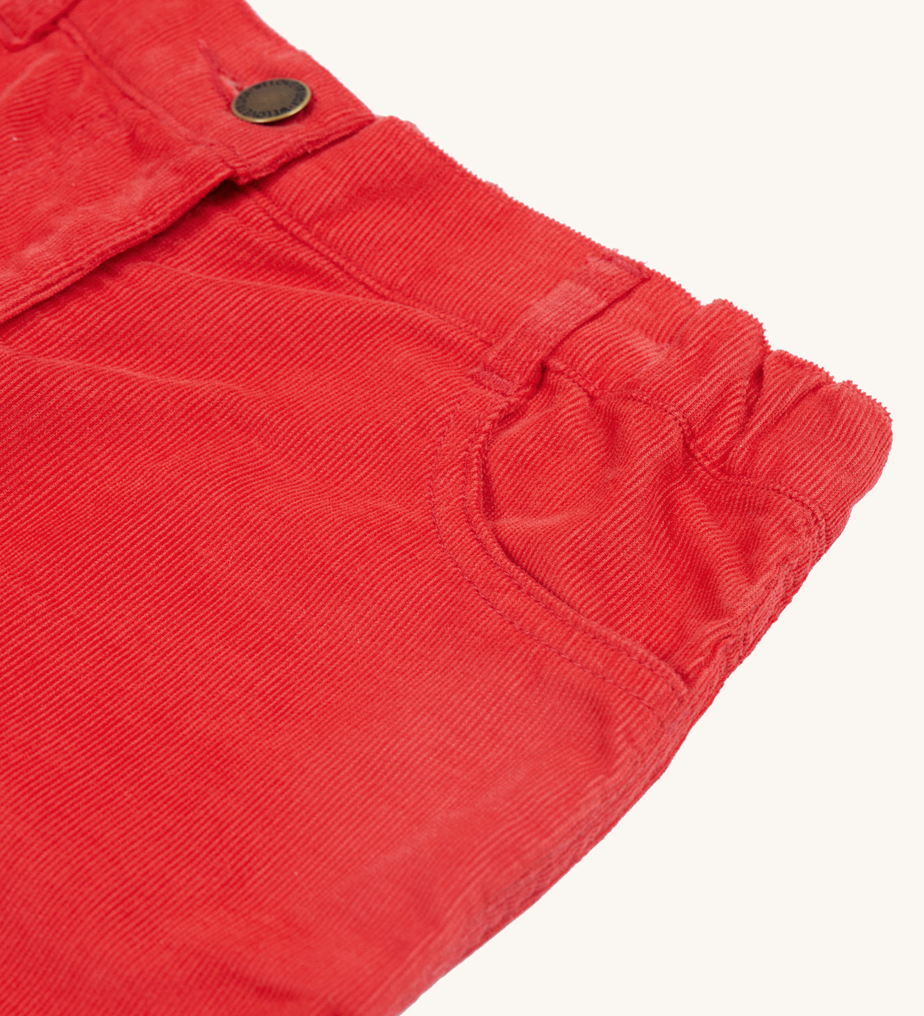 A closer look at the mock button and front pocket on the Frugi Clover Slim Cord Trousers - True Red