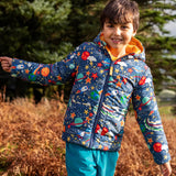 Child wearing the Frugi reversible toasty trail hooded jacket in explore the stars showing the repeating outer space design. 