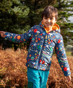 Child wearing the Frugi reversible toasty trail hooded jacket in explore the stars showing the repeating outer space design. 