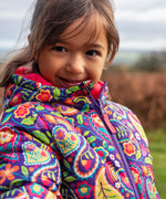 Child wearing the Frugi reversible toasty trail jacket showing close up of paisley design and front zip fastener